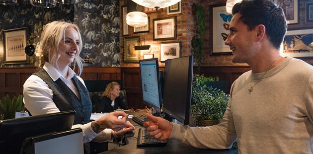 Pub worker greets guest at hotel check-in